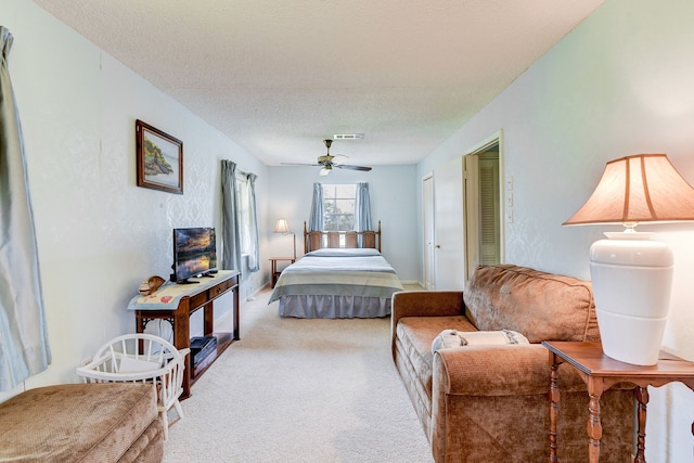 carpeted bedroom with ceiling fan and a textured ceiling