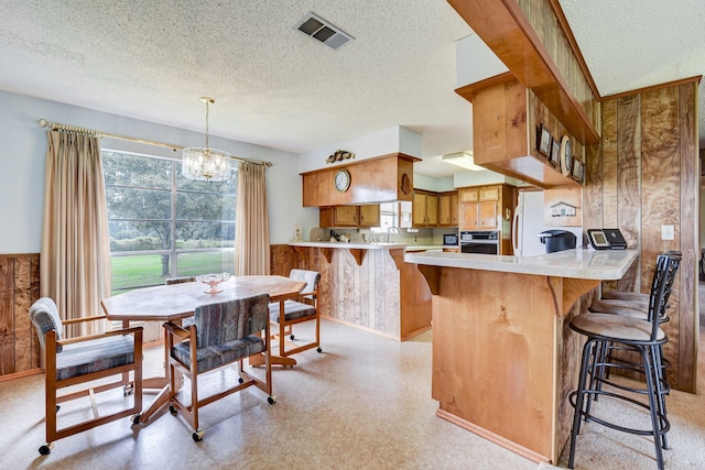 kitchen with kitchen peninsula, a textured ceiling, and wooden walls