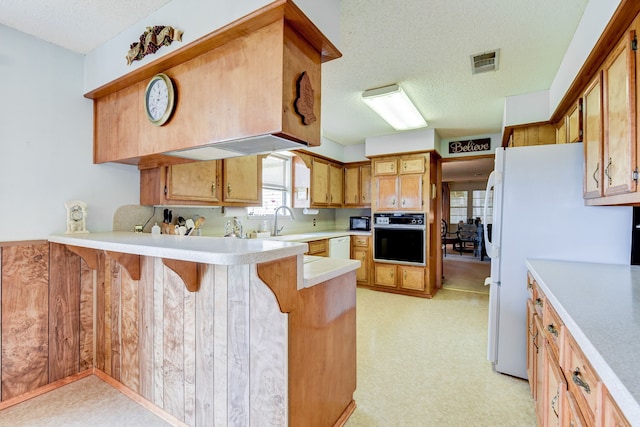 kitchen featuring a kitchen breakfast bar, kitchen peninsula, black appliances, and a textured ceiling