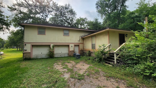 back of house featuring a lawn and a garage