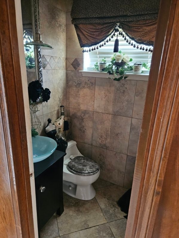 bathroom with vanity, toilet, and tile walls