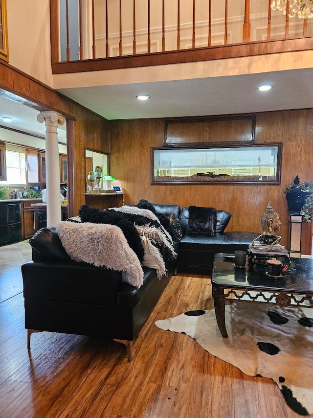 living room featuring wood-type flooring, decorative columns, and wood walls