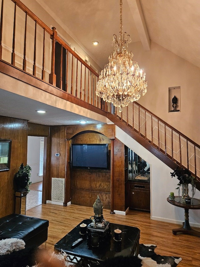 living room featuring a chandelier, vaulted ceiling with beams, light hardwood / wood-style floors, and wood walls