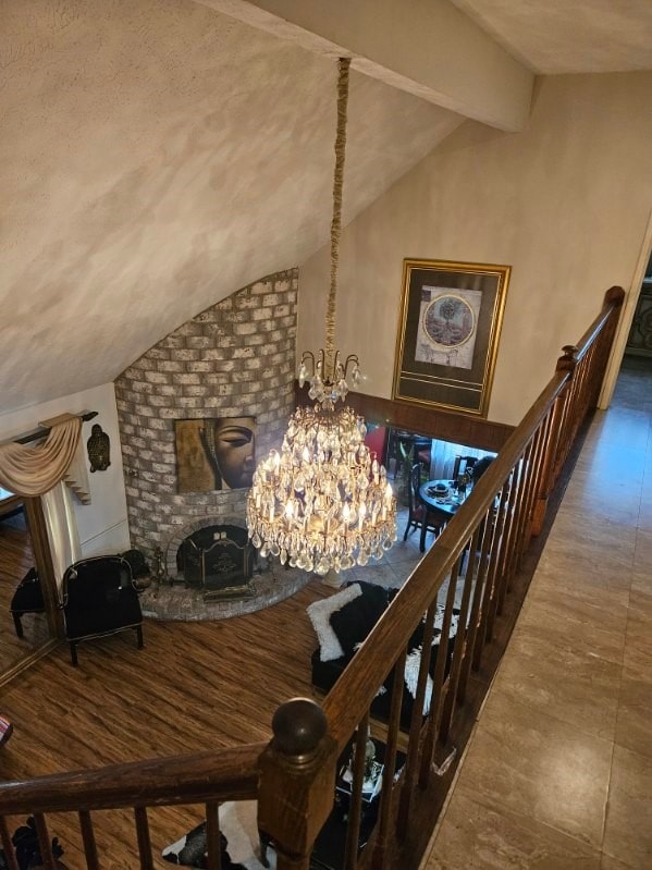 dining room with vaulted ceiling with beams, a brick fireplace, hardwood / wood-style flooring, and a notable chandelier