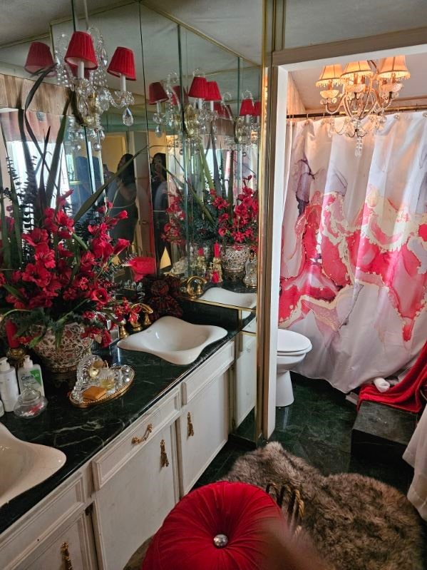 bathroom with vanity, an inviting chandelier, and toilet