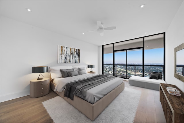 bedroom with ceiling fan, expansive windows, and wood-type flooring