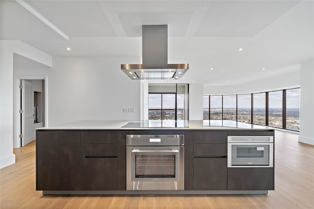 kitchen featuring island range hood, black electric stovetop, oven, and light hardwood / wood-style flooring