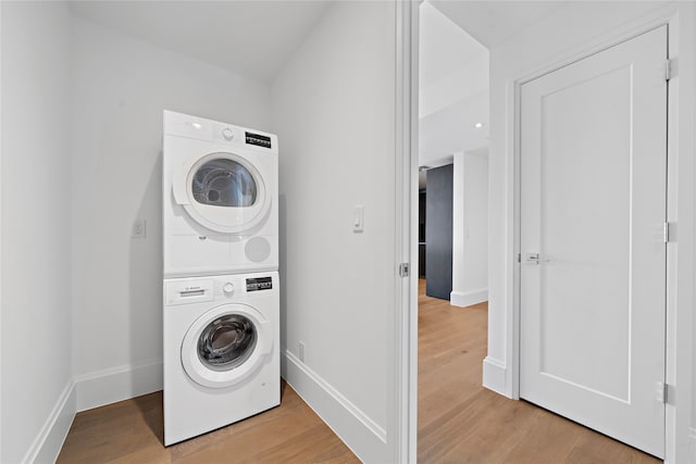 laundry room with light hardwood / wood-style flooring and stacked washer and clothes dryer