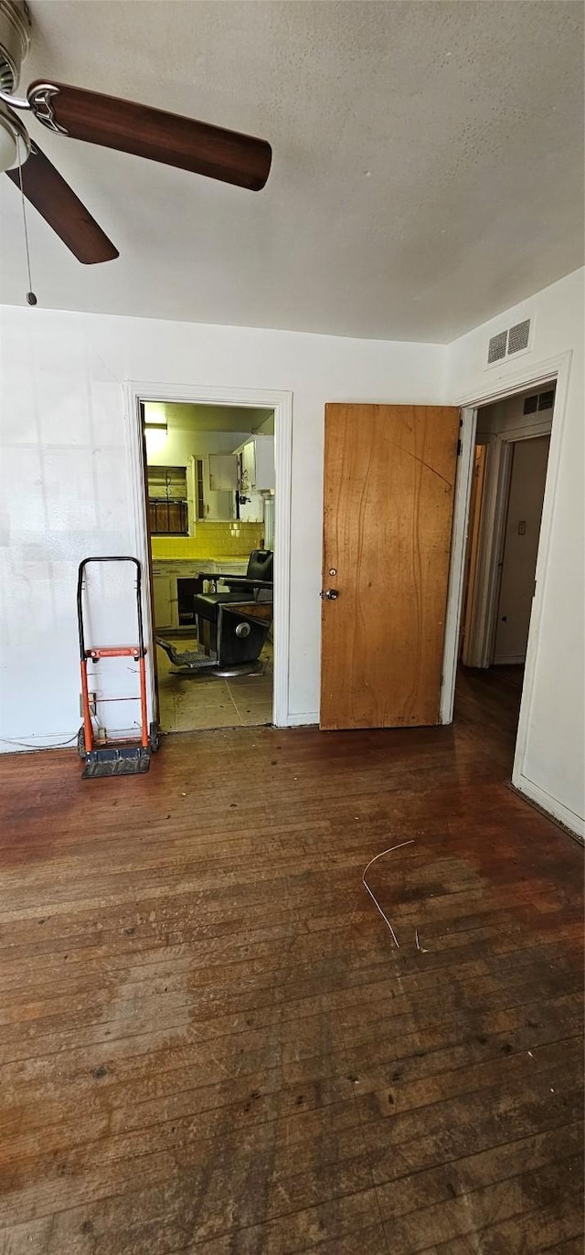 empty room with ceiling fan, a textured ceiling, and dark hardwood / wood-style flooring