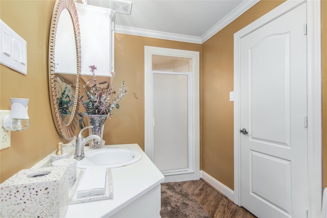 bathroom with ornamental molding, vanity with extensive cabinet space, an enclosed shower, and wood-type flooring