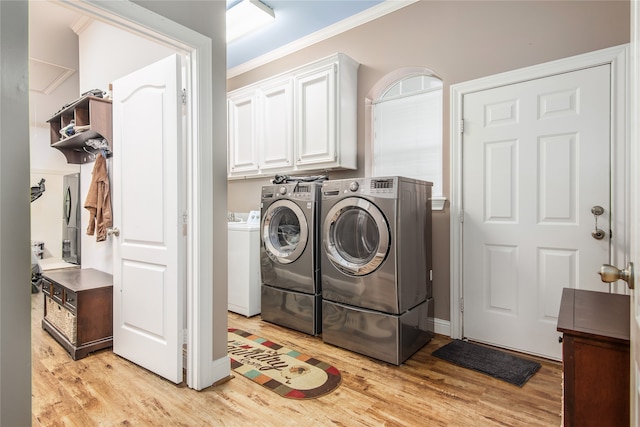 clothes washing area featuring separate washer and dryer, light hardwood / wood-style flooring, crown molding, and cabinets