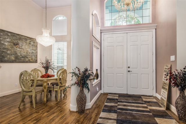 foyer featuring a chandelier, dark wood-type flooring, crown molding, and a high ceiling