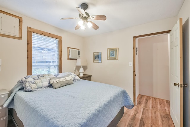 bedroom with ceiling fan, light wood-type flooring, and a wall mounted AC