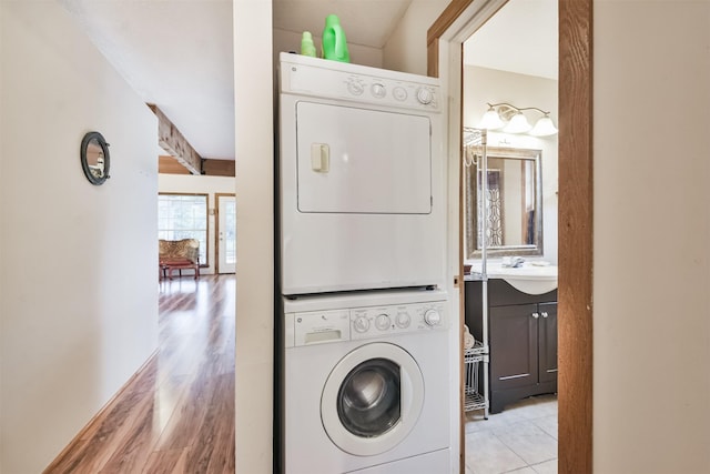 washroom with stacked washer / drying machine, light wood-type flooring, and sink