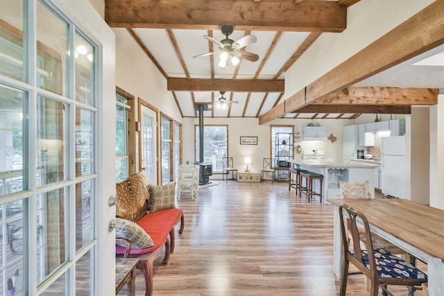 interior space with light wood-type flooring, vaulted ceiling with beams, and ceiling fan