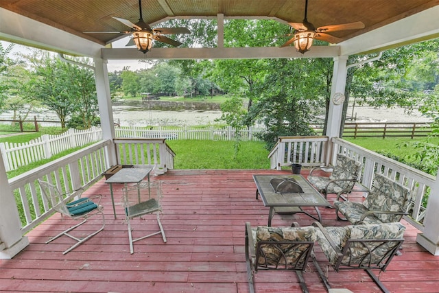 deck with a water view and ceiling fan