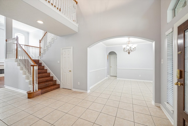 tiled foyer featuring a notable chandelier, a towering ceiling, and crown molding