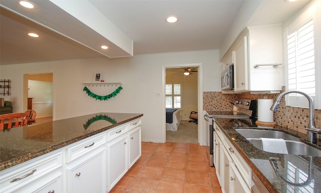 kitchen featuring sink, white cabinetry, stainless steel appliances, and dark stone counters