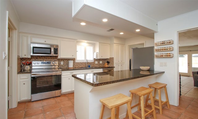 kitchen with decorative backsplash, a kitchen breakfast bar, stainless steel appliances, sink, and white cabinets