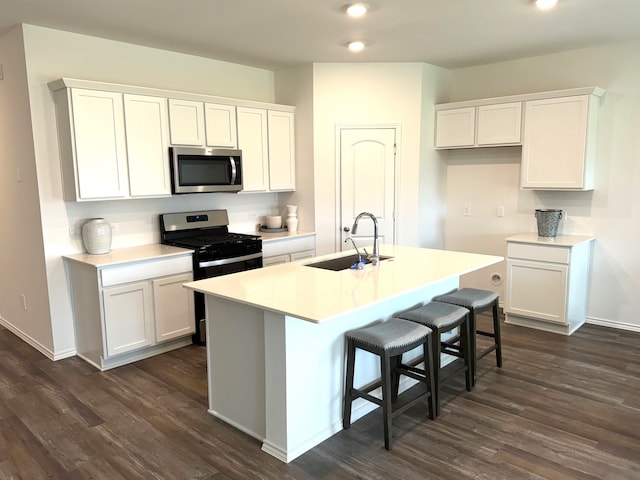 kitchen featuring sink, dark hardwood / wood-style flooring, stainless steel appliances, white cabinets, and a kitchen island with sink