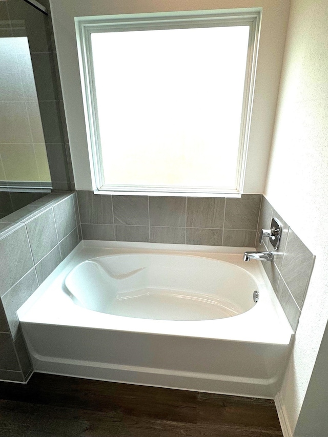 bathroom featuring a wealth of natural light, hardwood / wood-style floors, and a washtub