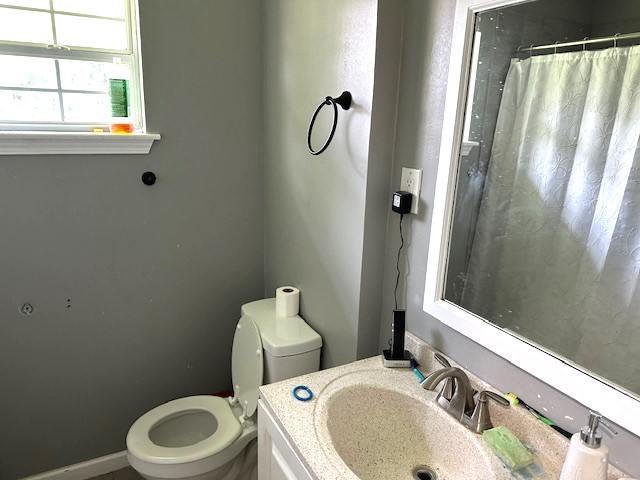 bathroom featuring a shower with shower curtain, vanity, and toilet