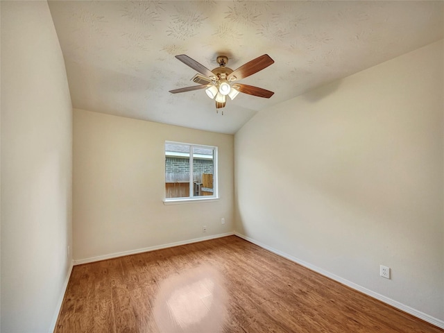 spare room with lofted ceiling, ceiling fan, wood-type flooring, and a textured ceiling