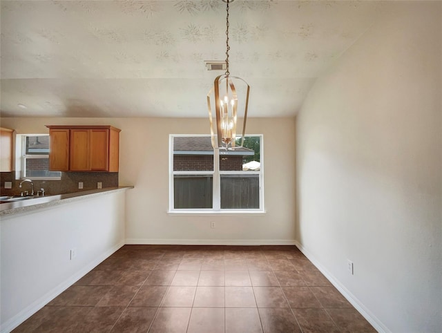 unfurnished dining area with lofted ceiling, dark tile patterned flooring, a notable chandelier, and sink