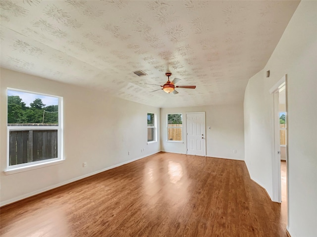 empty room featuring hardwood / wood-style floors, ceiling fan, and a wealth of natural light