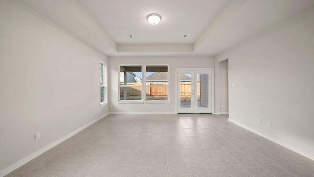 unfurnished room with a tray ceiling and french doors