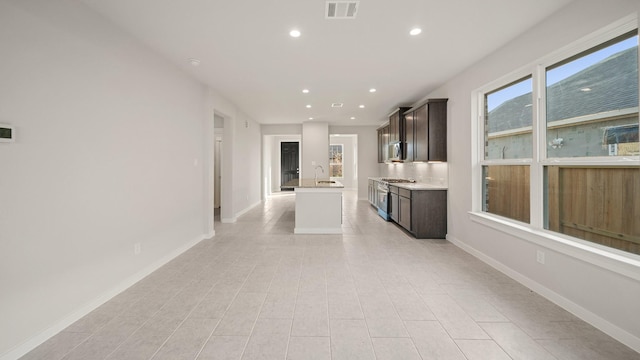 kitchen featuring a kitchen island with sink, dark brown cabinets, stainless steel appliances, and sink