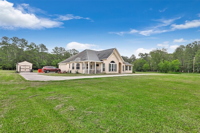 view of front of house with an outbuilding, driveway, a porch, and a front yard