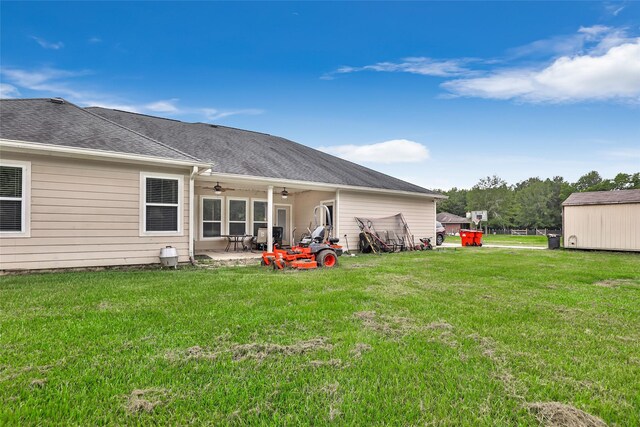 back of house featuring a patio area, ceiling fan, roof with shingles, and a yard