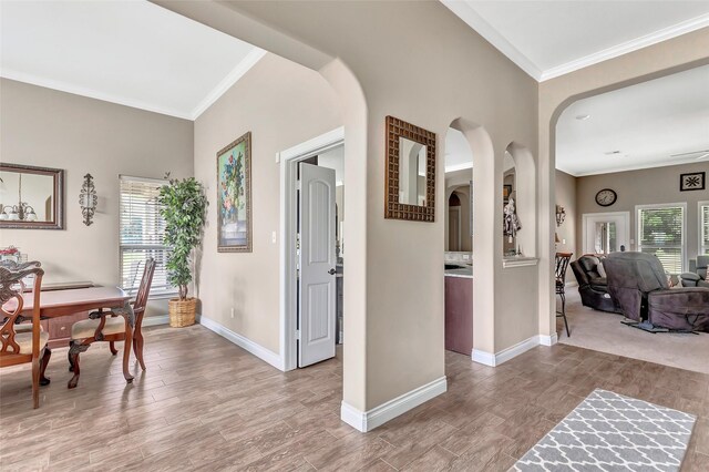 interior space featuring arched walkways, light wood finished floors, and crown molding