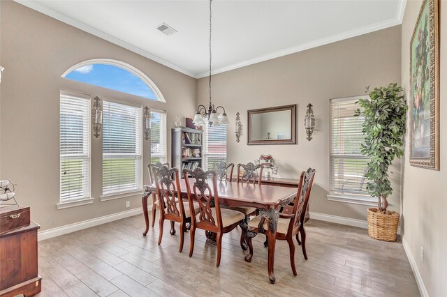 dining room featuring light wood finished floors, baseboards, visible vents, and ornamental molding