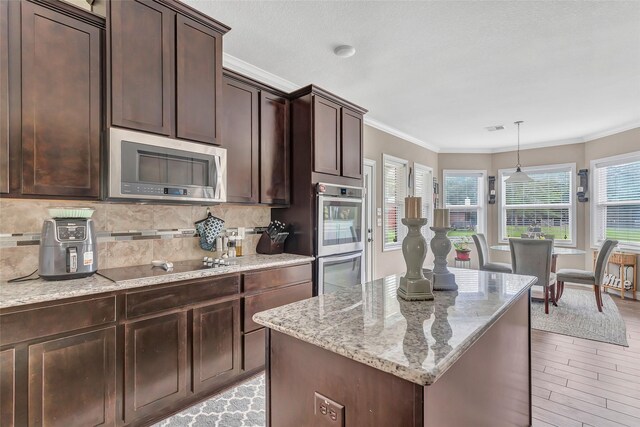 kitchen featuring ornamental molding, appliances with stainless steel finishes, light stone countertops, and tasteful backsplash