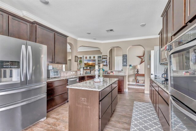 kitchen featuring appliances with stainless steel finishes, a center island, visible vents, and crown molding