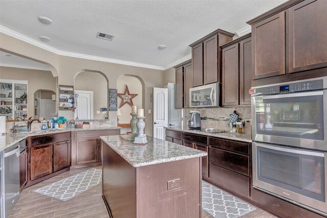 kitchen featuring appliances with stainless steel finishes, a kitchen island, visible vents, and light stone countertops