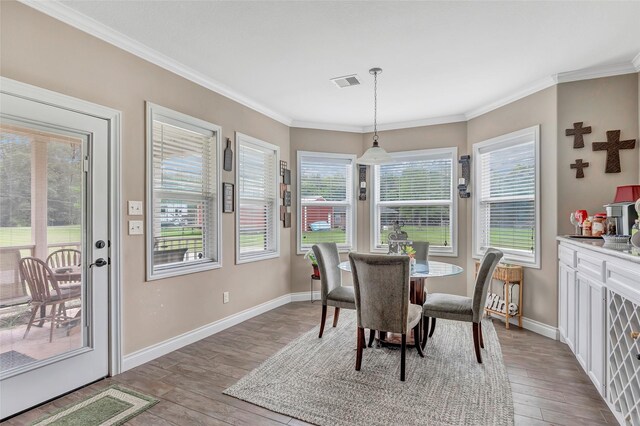 dining space with crown molding, hardwood / wood-style flooring, visible vents, and baseboards