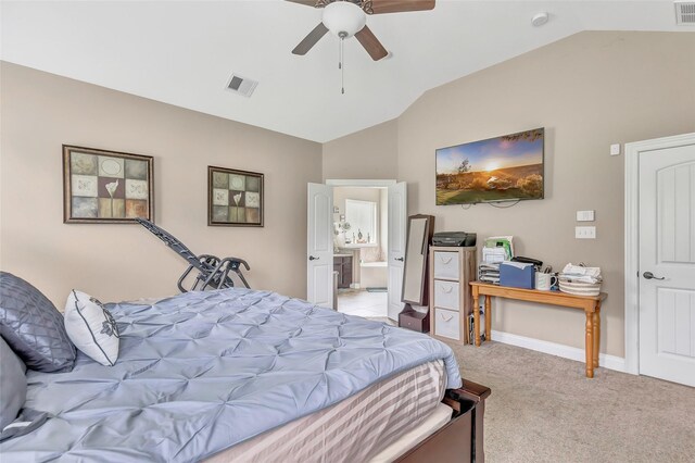 bedroom featuring light colored carpet, visible vents, vaulted ceiling, and ensuite bath