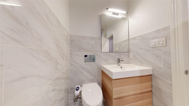 bathroom with vanity, toilet, and tile walls