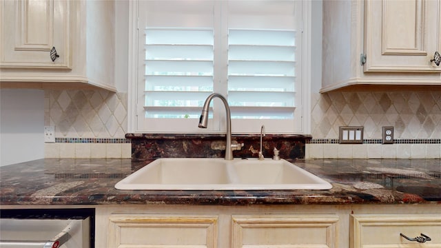 kitchen featuring tasteful backsplash, dark stone countertops, and sink