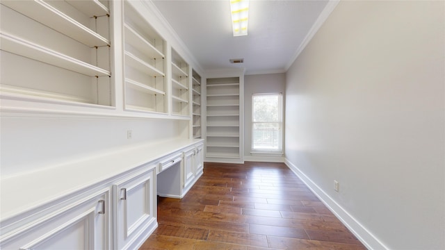 unfurnished office with dark hardwood / wood-style flooring, built in desk, and ornamental molding