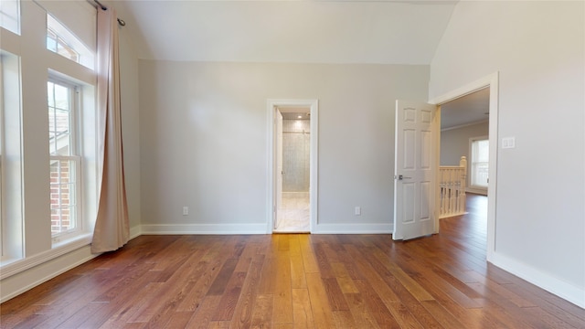 unfurnished bedroom with multiple windows, ensuite bathroom, and dark wood-type flooring