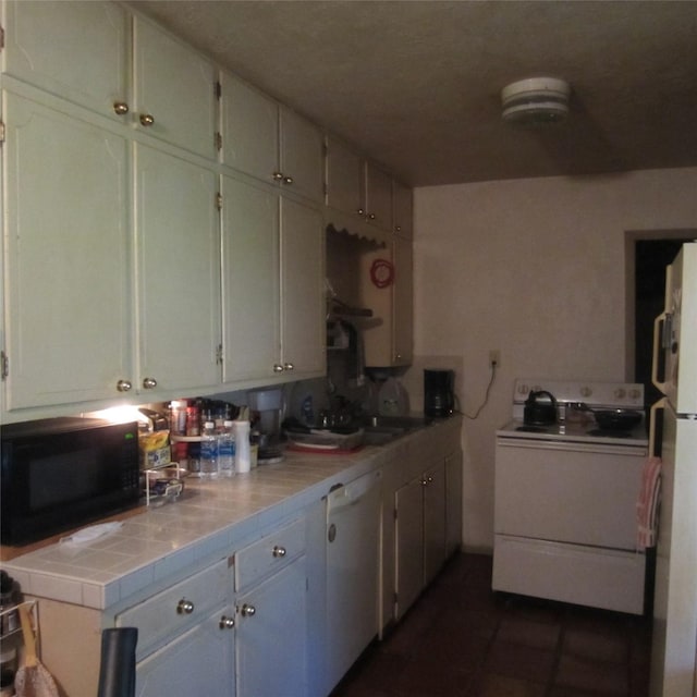 kitchen with white appliances, sink, and tile counters