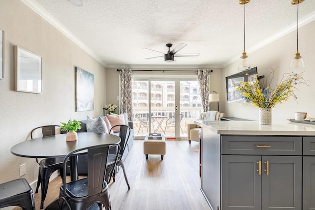 dining space featuring ceiling fan, crown molding, a textured ceiling, and light hardwood / wood-style flooring