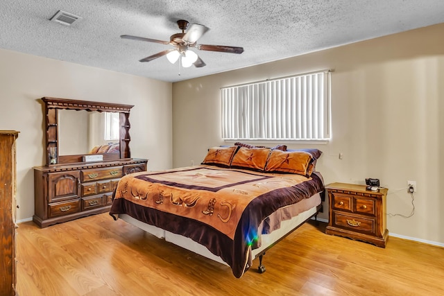 bedroom featuring ceiling fan, light hardwood / wood-style floors, and multiple windows