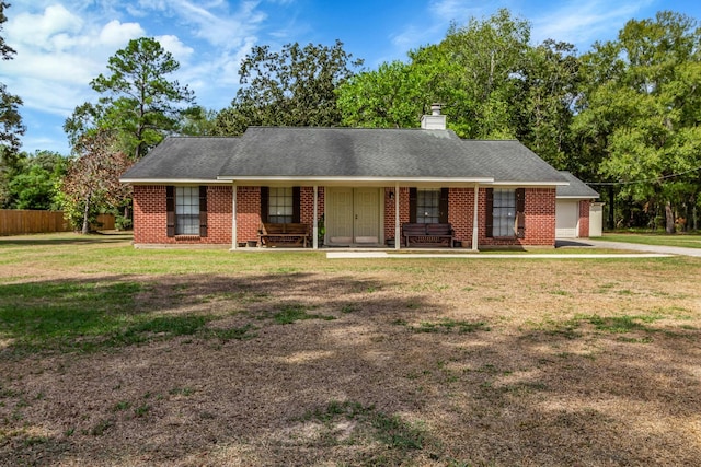 ranch-style house featuring covered porch, a garage, and a front yard