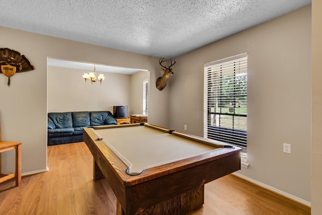 game room with an inviting chandelier, light hardwood / wood-style floors, a textured ceiling, and pool table