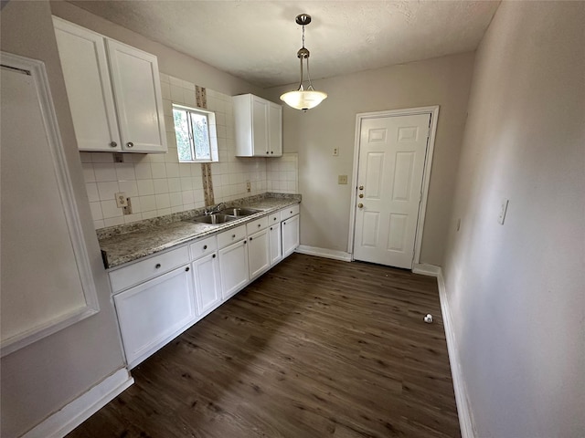 4520 Falls St, Houston, TX 77026 - kitchen with white cabinetry, decorative backsplash, dark wood-style flooring, and baseboards